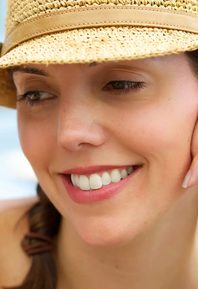a woman wearing a straw hat talking on a cell phone