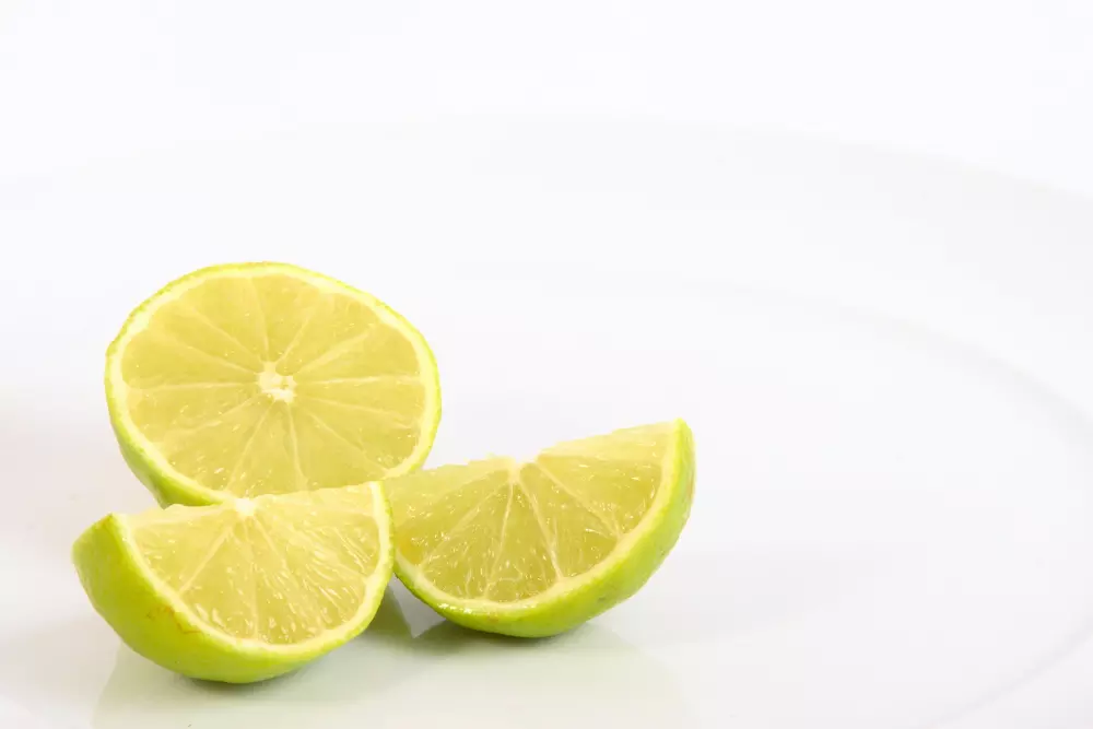 Drei Limetten halbiert auf einem weißen Teller