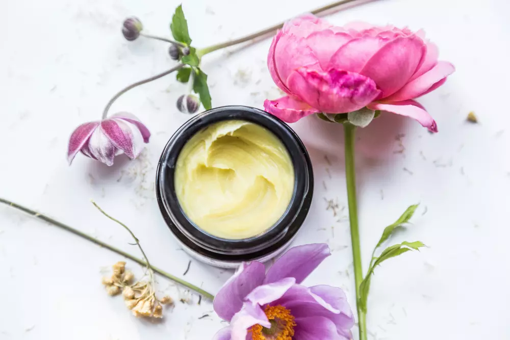 Ein Glas Sahne, das auf einem Tisch neben Blumen steht