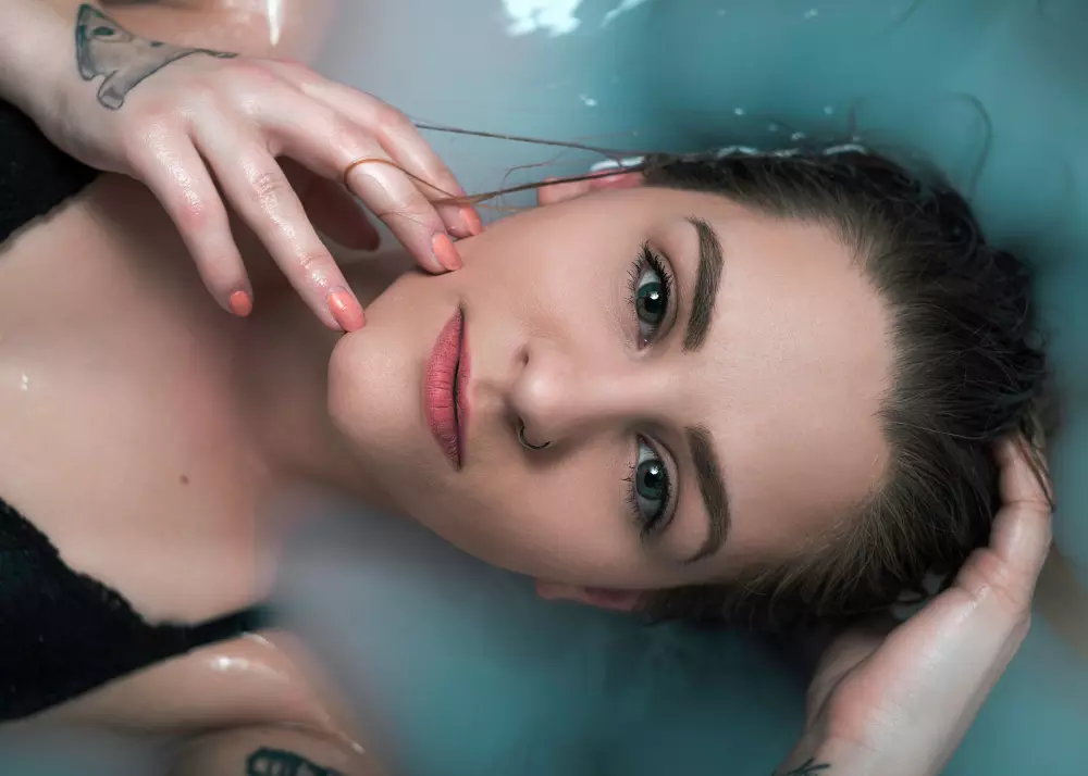 Eine Frau liegt in einer Badewanne mit den Händen auf dem Kopf.