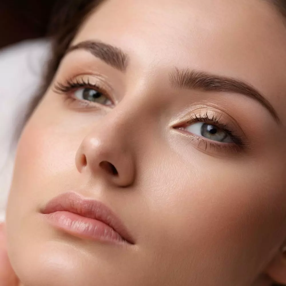 Nahaufnahme einer sanften Anwendung des flüssigen Lifting-Serums um die Augen herum, drinnen in einer beruhigenden und professionellen Spa-ähnlichen Umgebung, die Stimmung ist ruhig und tröstlich, Fotografie im Close-up-Stil mit weichem Fokus und Umgebungslicht.
