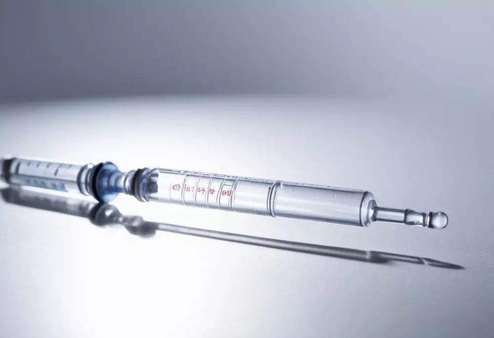 Nahaufnahme einer Hyaluronsäure-Füllerspritze, fokussiert auf das klare Gel im Inneren, in einem klinischen Umfeld mit sterilem, weißem Hintergrund, fotografischer Stil mit scharfer Schärfe und hellem Licht.