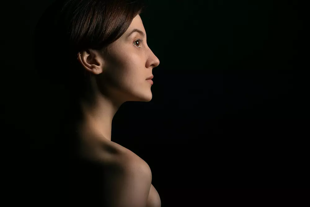 Das Profil einer Frau wird im Dunkeln gezeigt.