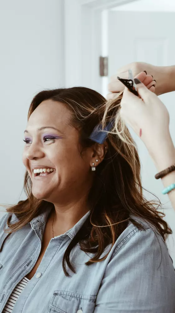 Eine Frau, die von einer anderen Frau mit einer Schere die Haare geschnitten bekommt.
