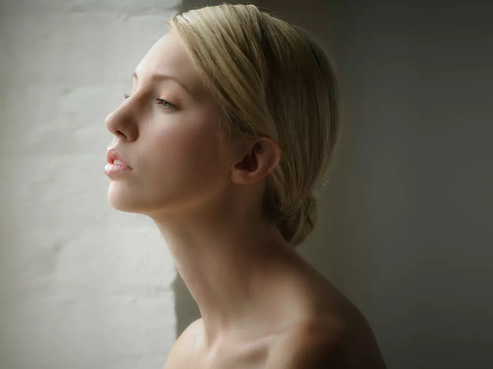 Eine Nahaufnahme des Gesichts einer Frau mit einer Ziegelwand im Hintergrund