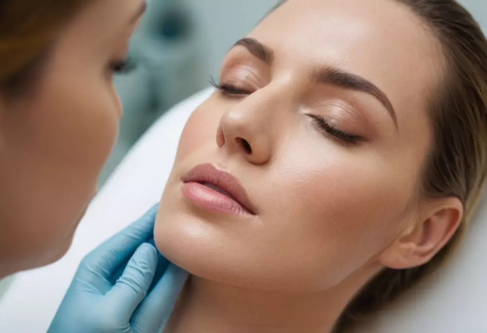 Nahaufnahme eines Profis, der einem Patienten in einer hellen, modernen Dermatologieklinik eine dezente Menge Gesichtsfüller aufträgt, weichgezeichnete Fotografie mit hoher Auflösung.