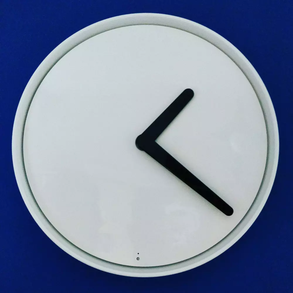 Eine weiße Uhr mit schwarzem Zifferblatt auf einer blauen Oberfläche