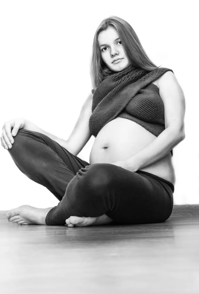 Una mujer embarazada está sentada en el suelo