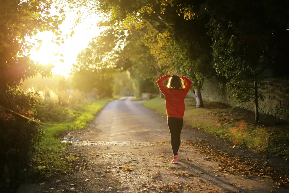 una mujer con una camisa roja está corriendo por un camino de tierra
