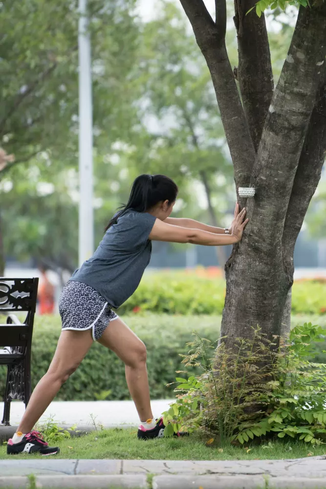 Eine Frau lehnt an einem Baum auf einer Parkbank.