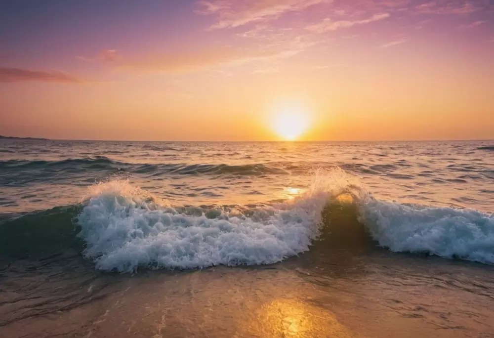 Ein ruhiger Sonnenaufgang über einem ruhigen Meer, der neue Anfänge und das Überwinden von Herausforderungen symbolisiert, fotografiert mit einer Panoramaaufnahme und warmem natürlichem Licht.