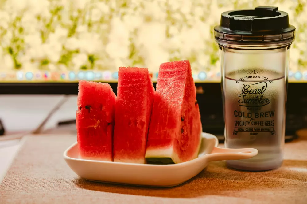 Ein Teller mit Wassermelonen-Scheiben neben einer Tasse Kaffee