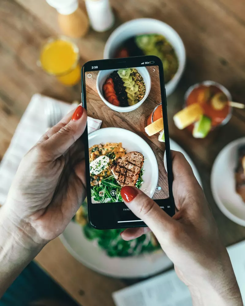 Eine Frau, die Essen mit ihrem Handy fotografiert.