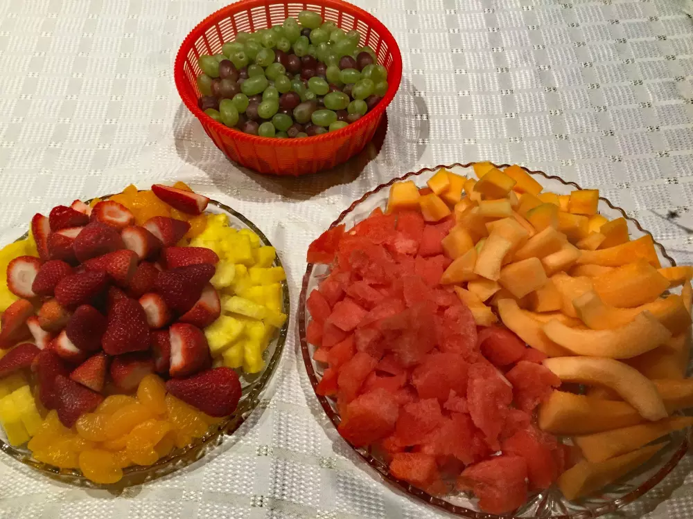 Ein Tisch, der mit Schalen voller Obst und einer Schale mit Trauben bedeckt ist.
