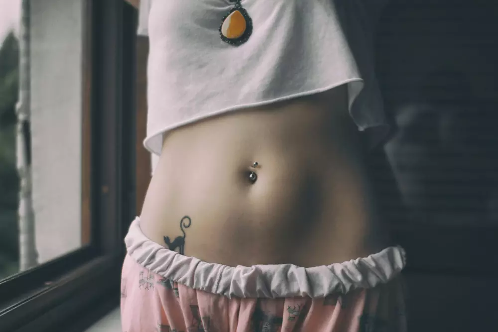 a close up of a woman's stomach with a piece of jewelry on it