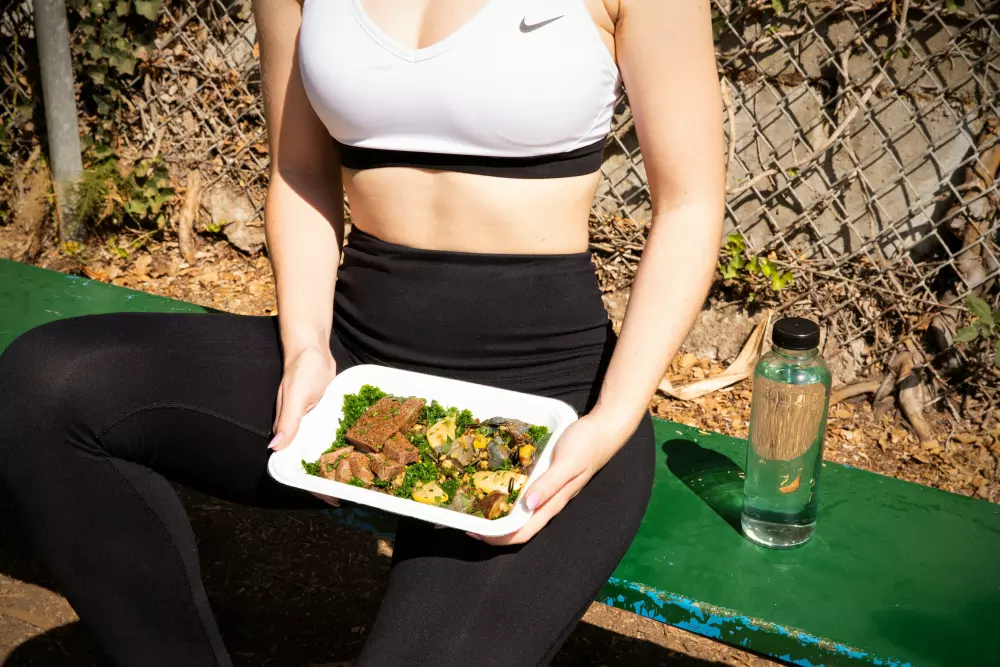 a woman sitting on a bench holding a plate of food