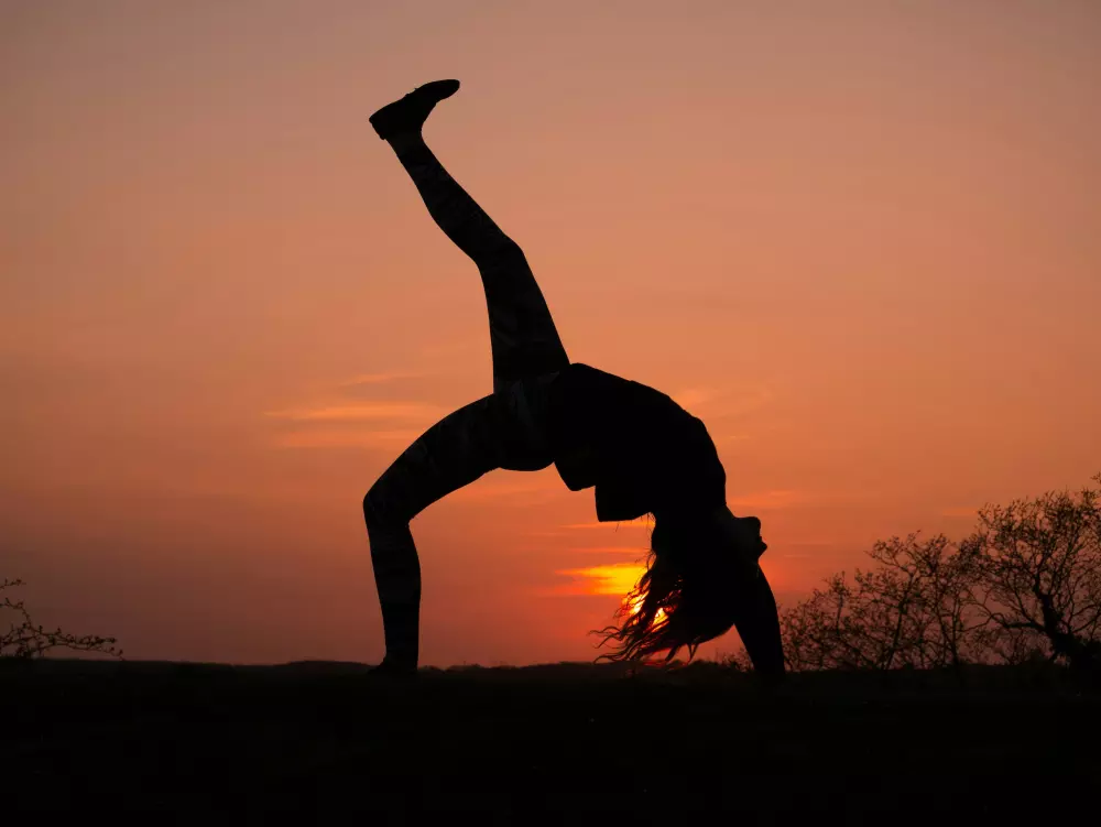 Eine Frau macht einen Handstand vor einem Sonnenuntergang