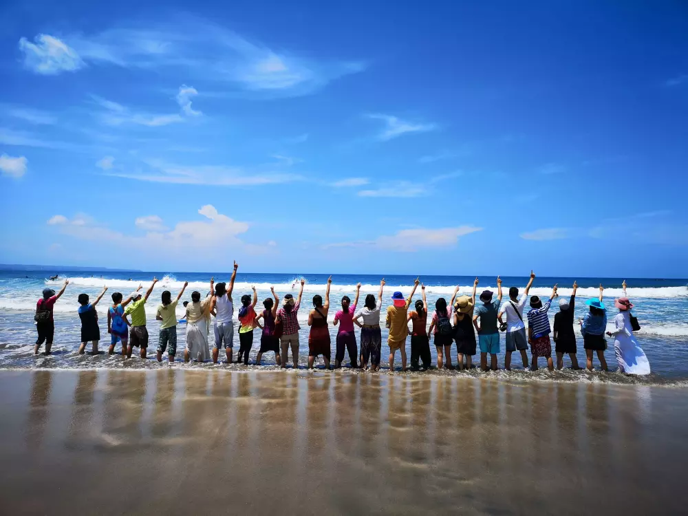 Eine Gruppe von Menschen steht auf einer sandigen Strandspitze.
