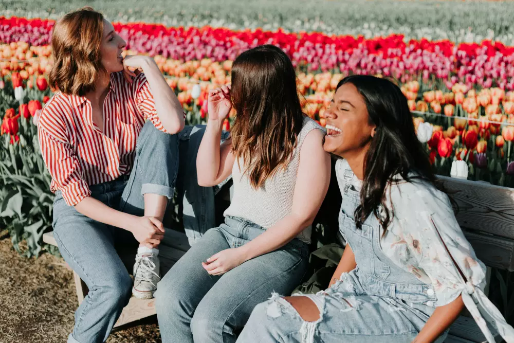 three women sitting on a bench in a field of tulips