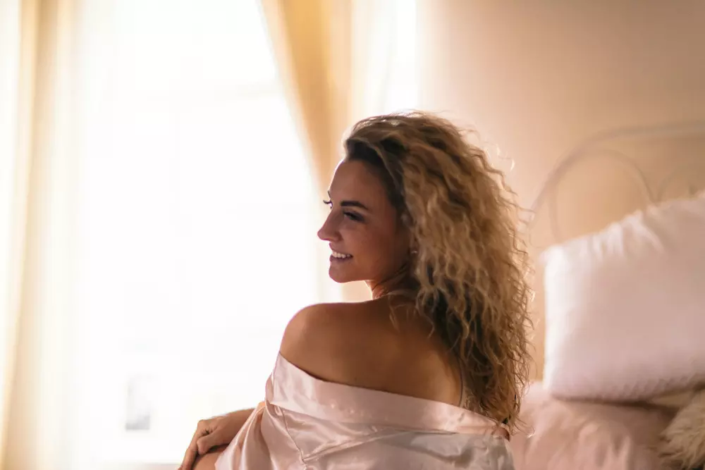 a woman in a white dress sitting on a bed
