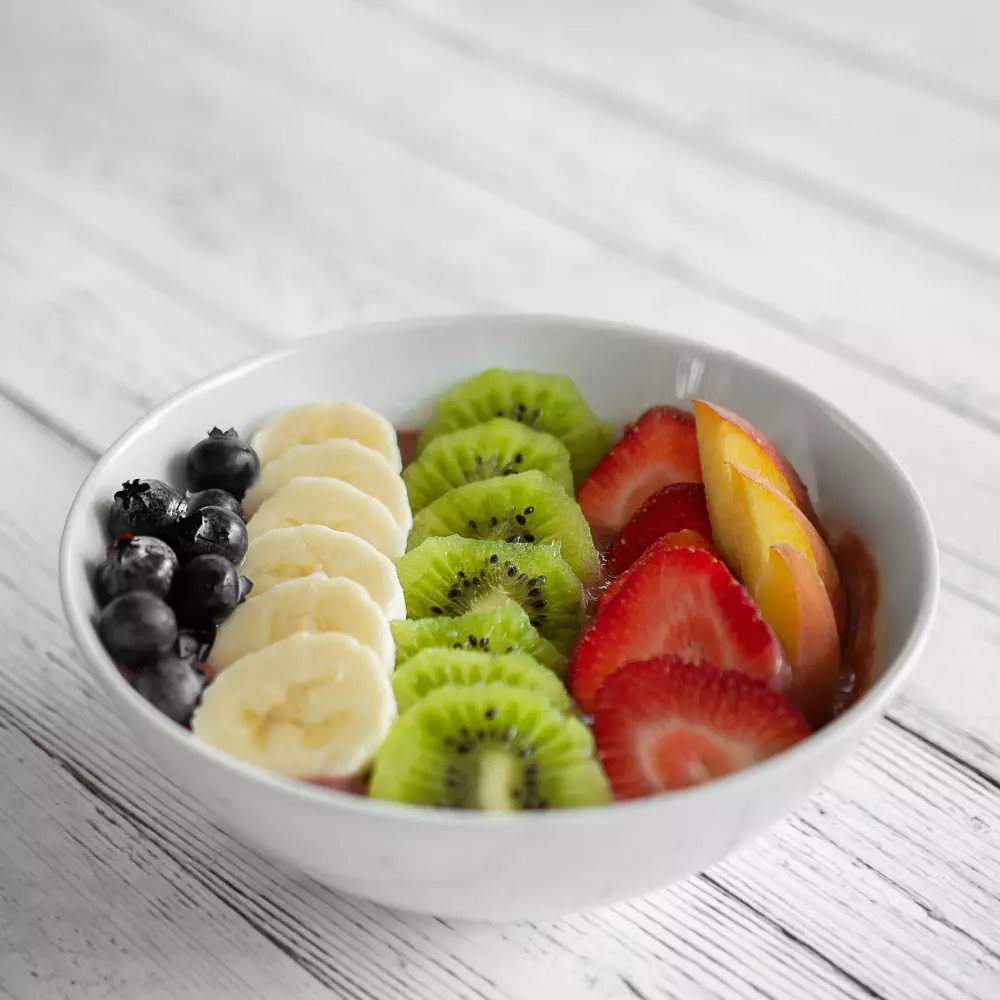 a white bowl filled with fruit on top of a wooden table
