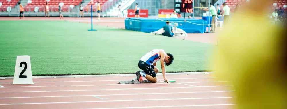 Ein Mann kniet oben auf einer Rennstrecke.
