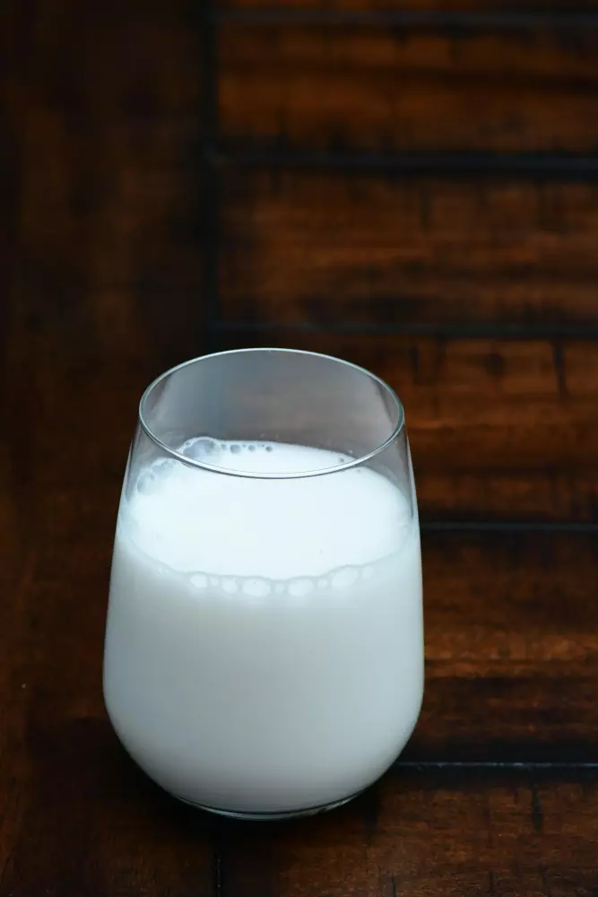 un vaso de leche sobre una mesa de madera