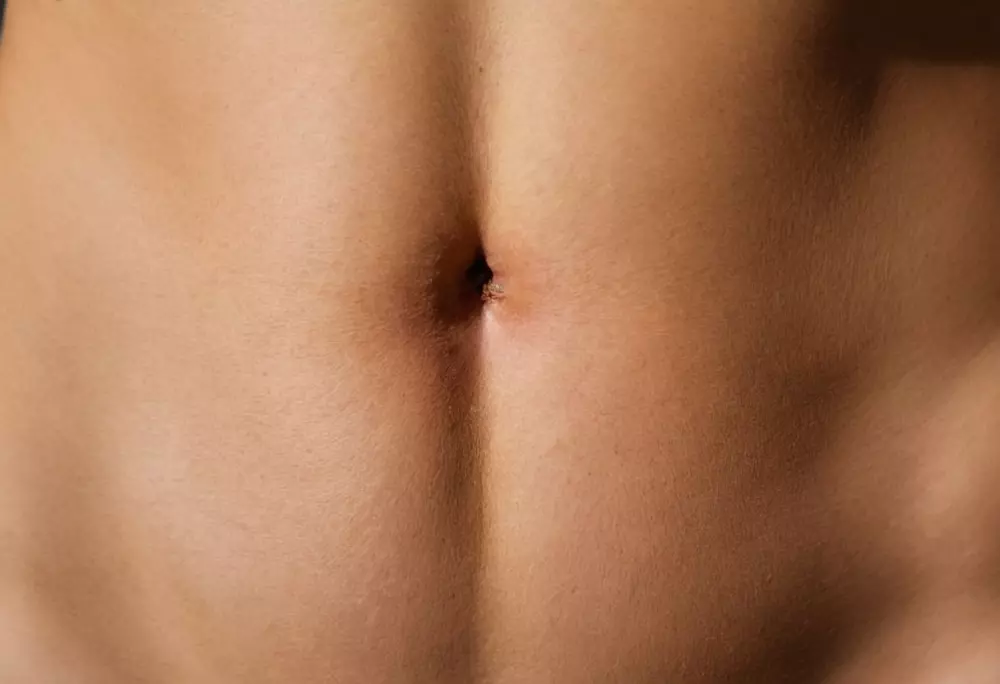 Nahaufnahme eines Bauchnabels auf klarer Haut, natürliches Licht, hohe Auflösung, fotografischer Stil, umgesetzt durch detaillierte Makrofotografie.