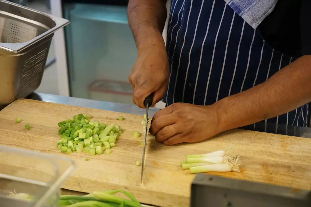 Ein Mann schneidet Zwiebeln auf einem hölzernen Schneidebrett.