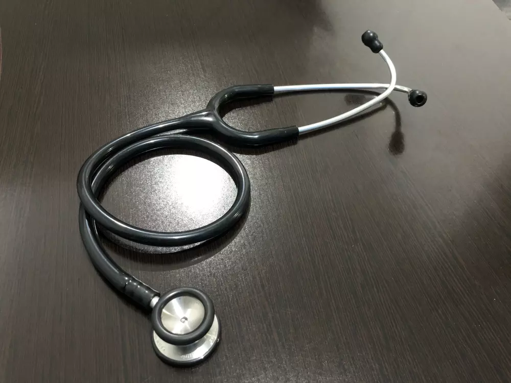 Ein Stethoskop liegt auf einem hölzernen Tisch.