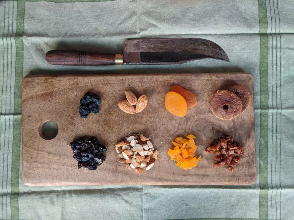 Ein hölzernes Schneidebrett, das mit Früchten und Nüssen belegt ist.