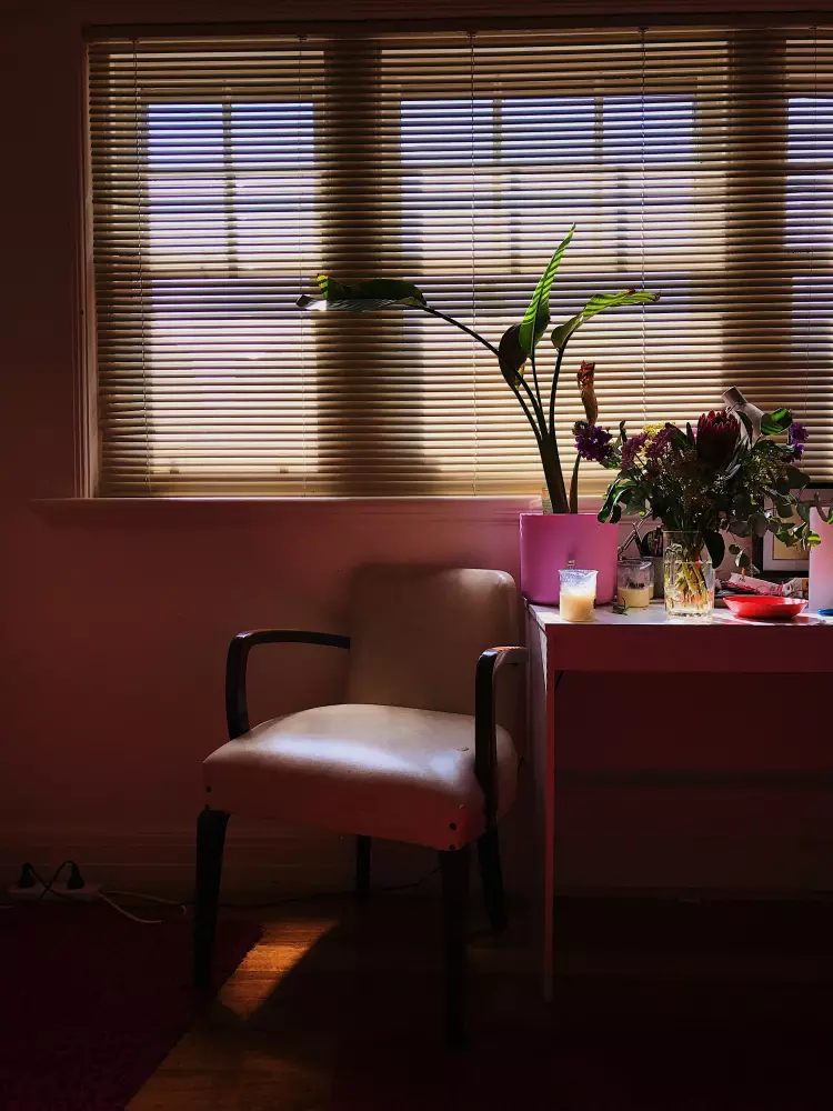 a chair sitting next to a table with a vase of flowers on it