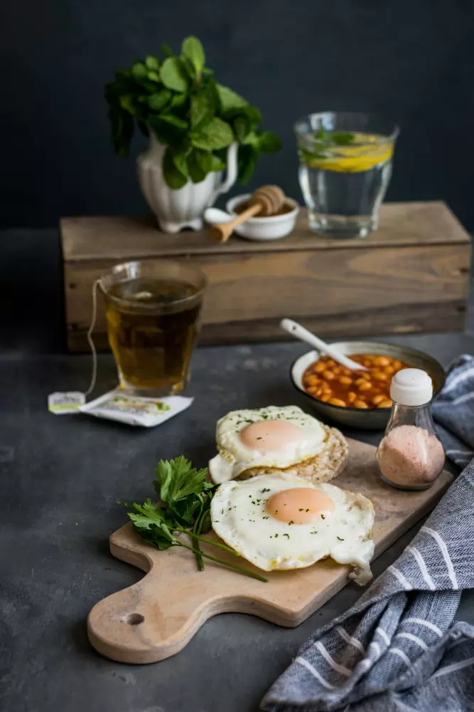 a wooden cutting board topped with eggs next to a cup of tea
