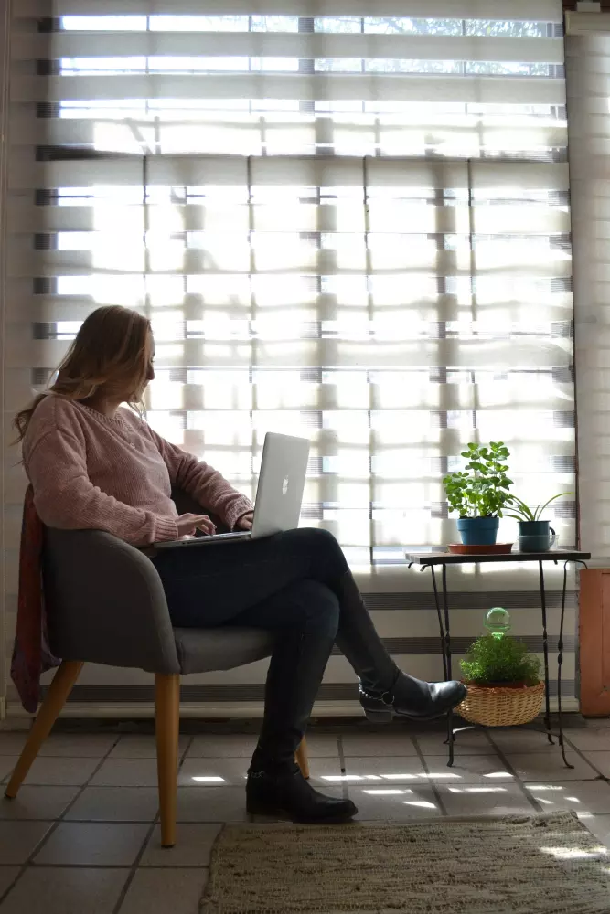 a woman sitting in a chair using a laptop computer