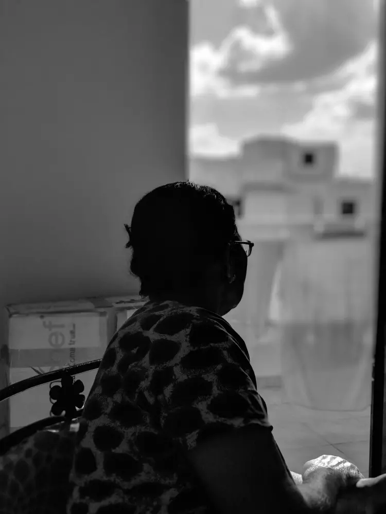 a person sitting in a chair looking out a window