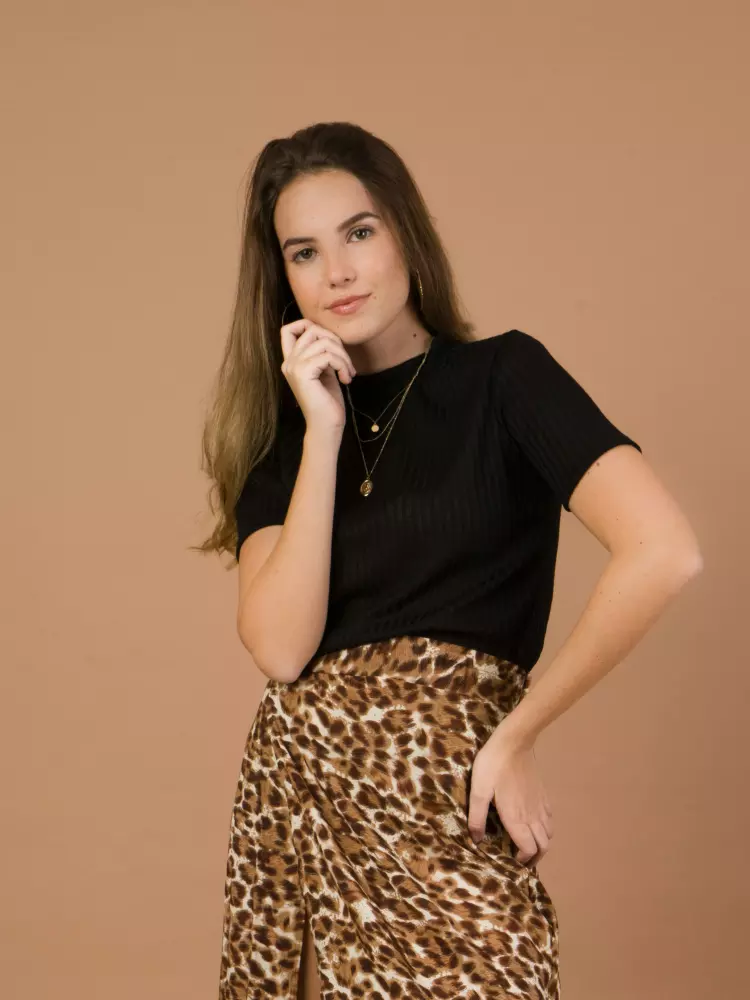 Eine Frau posiert mit der Hand am Kinn.