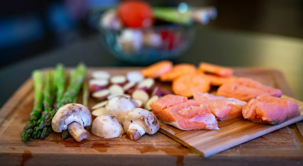 Ein hölzernes Schneidebrett, das mit verschiedenen Arten von Gemüse bedeckt ist.
