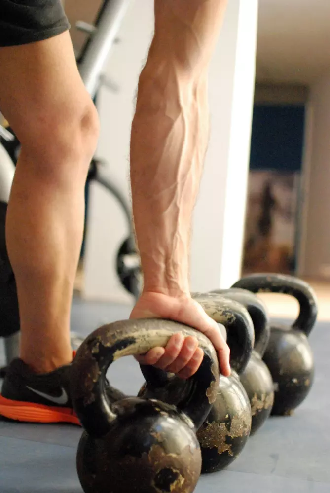 Ein Mann hält eine Kanne, während er neben einer Reihe von Kannen steht.