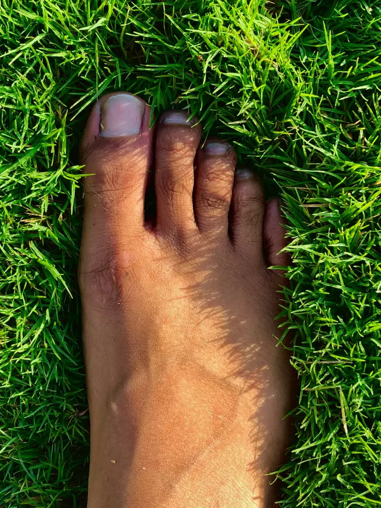 Ein nackter Fuß einer Person im Gras