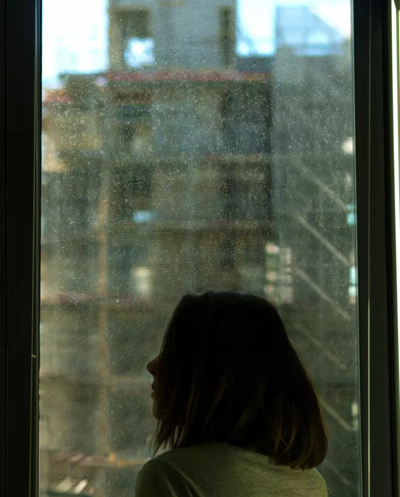 Eine Frau schaut aus dem Fenster auf eine Baustelle.