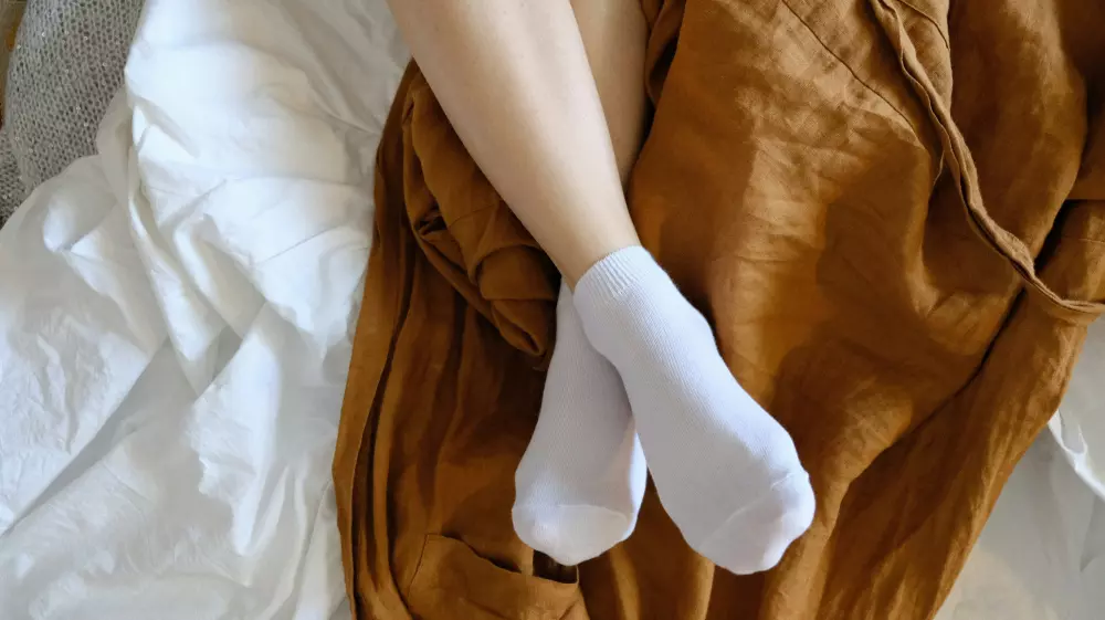 Eine Person mit weißen Socken liegt auf einem Bett.
