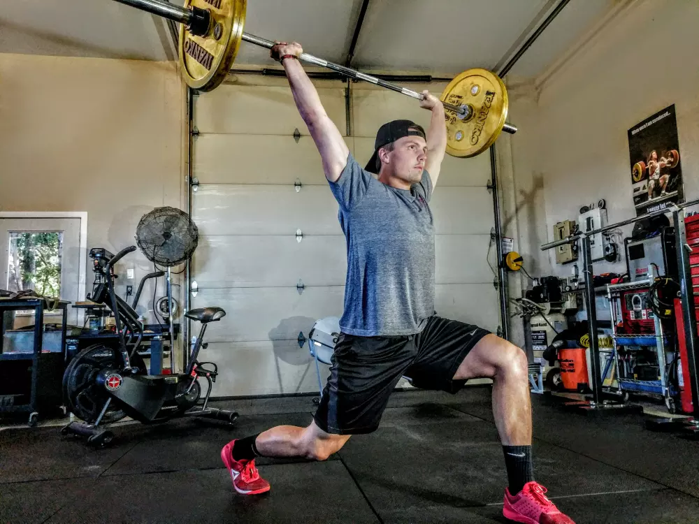 Ein Mann macht eine Kniebeuge mit einer Langhantel.