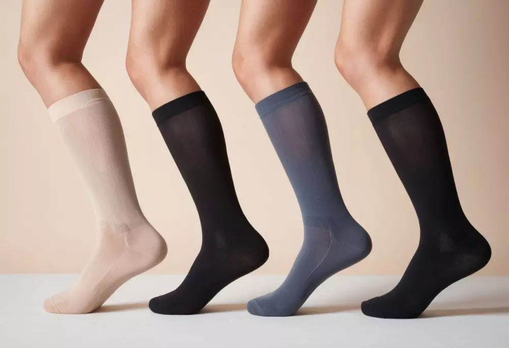 Mehrere Arten von Kompressionsstrümpfen, ordentlich auf einem hellen Hintergrund angeordnet, jeder mit einem kleinen Etikett versehen, um seine Kompressionsklasse anzuzeigen, wurden in einer hochauflösenden Nahaufnahme mit weichem Licht fotografiert, um sich auf die Details des Stoffs und der Etiketten zu konzentrieren.