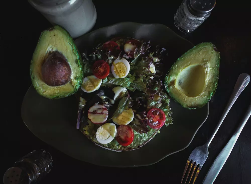Ein Teller mit Essen mit Avocado und Salat darauf