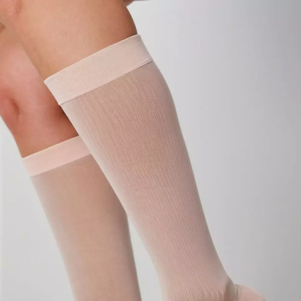 Nahaufnahme von Beinen, die Kompressionsstrümpfe tragen, detaillierte Ansicht des Stoffes und der Passform, in einem klinischen Umfeld mit neutralem Hintergrund, praktisch und informativ, Fotografie, Aufnahme mit einem Makroobjektiv, hohe Detailgenauigkeit.