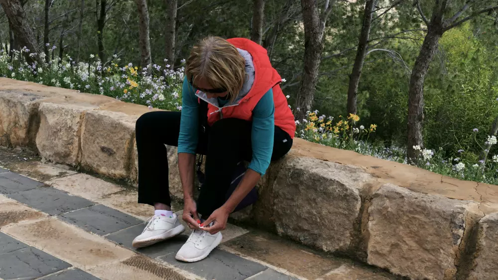 Eine Frau sitzt auf einer Steinmauer und bindet ihre Schuhe.