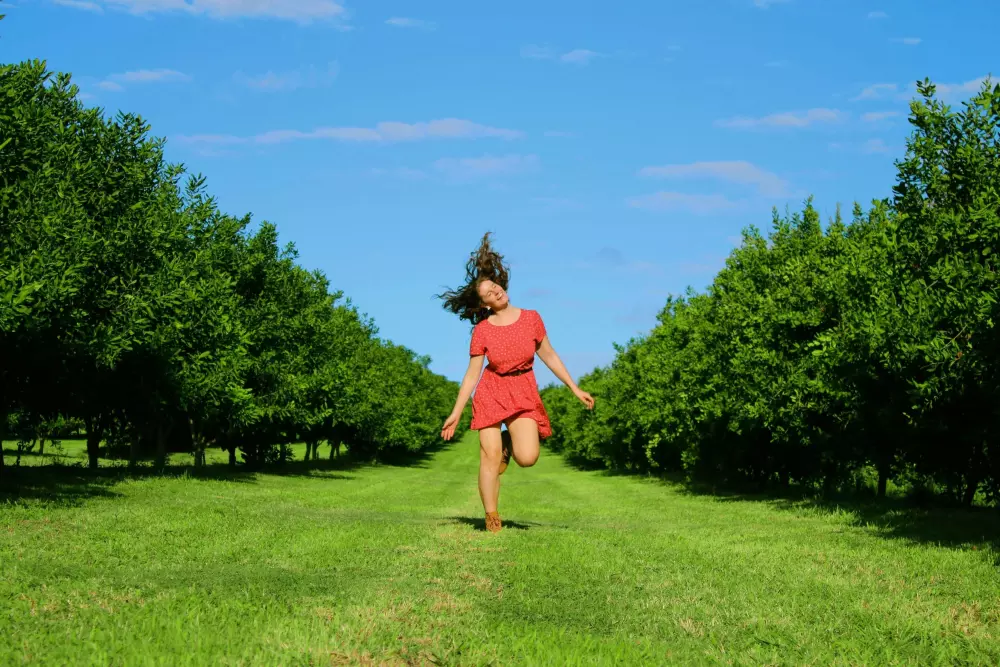 Eine Frau in einem roten Kleid rennt durch ein Feld.