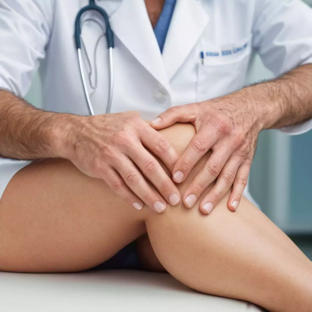 Die Hände des Arztes halten ein Knie-Modell in einem hellen Klinikbüro, was eine professionelle Beratung symbolisiert. Das Foto ist detailliert auf das Modell und die Hände fokussiert und wurde mit einem Makroobjektiv und weichem Studiolicht für Klarheit aufgenommen.