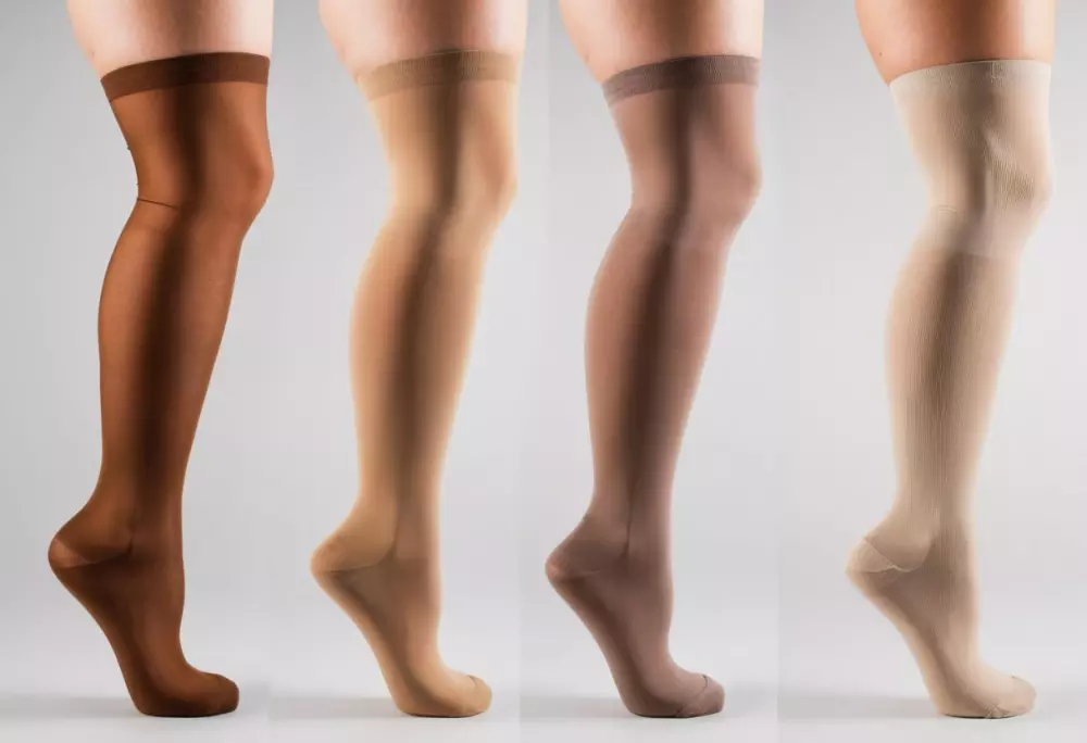 Eine ordentlich angeordnete Auswahl verschiedener Kompressionsstrümpfe auf einem einfarbigen Hintergrund, die verschiedene Stile und Zwecke hervorheben. Fotografiert in einer hellen und klaren Umgebung mit einer mittleren Aufnahme und einem scharfen Fokusobjektiv, um Texturdetails zu zeigen.